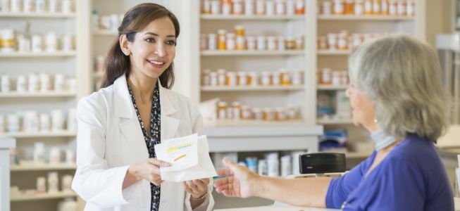 Apothekerin zeigt Kundin etwas auf der Rückseite einer Arzneiverpackung